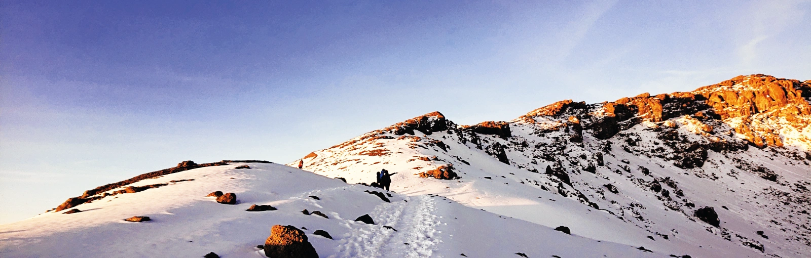 Snow-covered trail leading toward Uhuru Peak on Mount Kilimanjaro under a clear sky