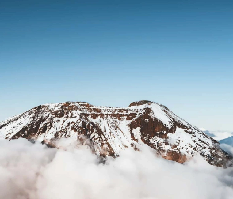 Mount Kilimanjaro with its snow-capped peak viewed from the surrounding savannah, a highlight of Tanzania trekking tours.