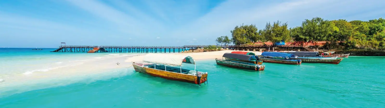 Traditional wooden dhow boats sailing on the clear waters of the Indian Ocean in Zanzibar.